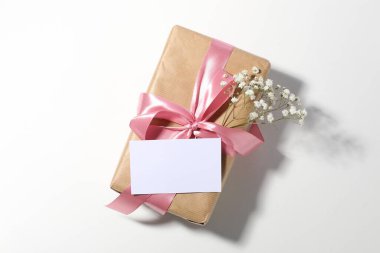 Boş kart, hediye kutusu ve beyaz arka planda güzel çiçekler, üst manzara.