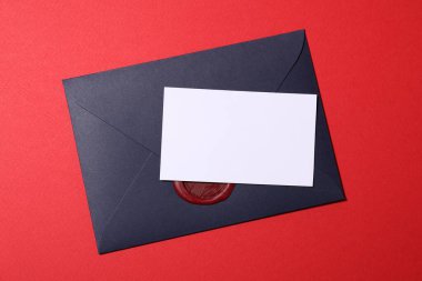 Blank card and envelope on red background, top view