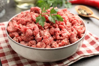 Maydanozlu çiğ et ve gri masada baharatlar, yakın plan.