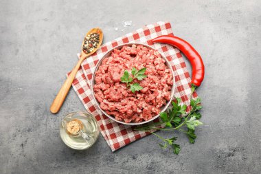 Raw minced meat with parsley and spices on grey table, flat lay
