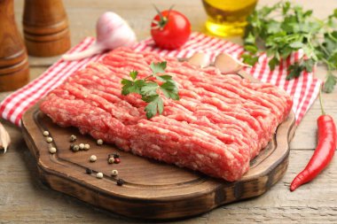 Maydanozlu çiğ et ve ahşap masada baharatlar, yakın plan.