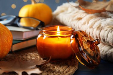 Mavi ahşap masada yanan mum ile sonbahar kompozisyonu bulanık ışıklara karşı, yakın çekim