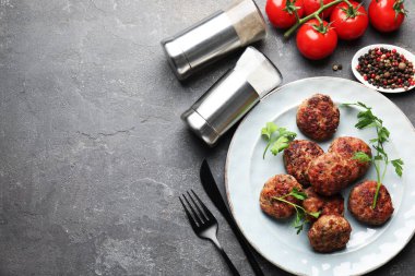 Salt and pepper shakers, meatballs on grey table, flat lay. Space for text