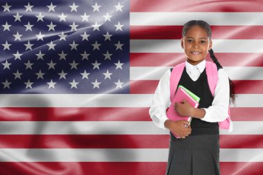 ABD bayrağına karşı sırt çantası ve defterleri olan küçük bir kız. Dil okulu
