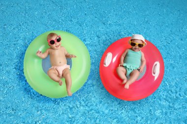 Güneş gözlüklü, yüzme havuzunda şişme yüzüklü şirin bebekler. Üst görünüm