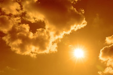 Sıcak yaz havasında turuncu gökyüzünde parlak güneş ve bulutlar