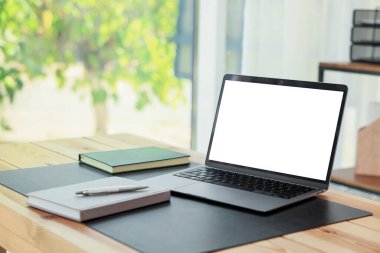 Boş beyaz ekranlı ve masadaki kırtasiyeli dizüstü bilgisayar. Rahat ev işyeri