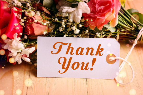 Спасибо тегу и цветам на деревянном столе. Огни Боке