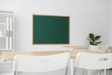 Boş yeşil karatahta, masalar, sandalyeler, raf ünitesi ve bitki sınıfı