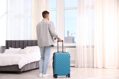 Bavullu bir adam pencereden dışarı bakıyor.