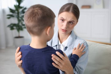 Anne, üzgün oğlunu evde destekleyip kucaklıyor.