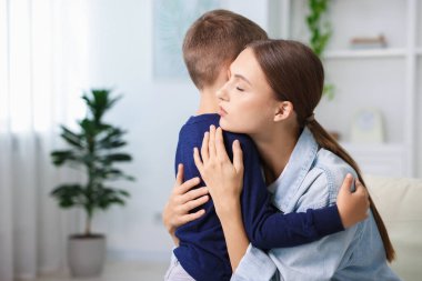 Anne, üzgün oğlunu evde destekleyip kucaklıyor.