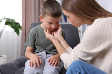 Anne üzgün oğlunu evde destekliyor, yakın plan.