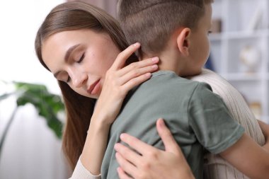 Anne, üzgün oğlunu evde destekleyip kucaklıyor.