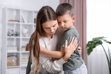 Anne, üzgün oğlunu evde destekleyip kucaklıyor.