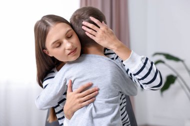 Anne, üzgün oğlunu evde destekleyip kucaklıyor.