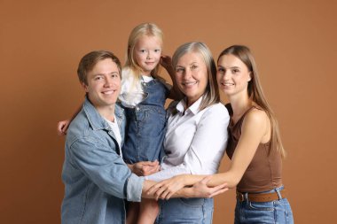 Kahverengi arka planda oğlu ve ailesi olan yaşlı bir kadının portresi.