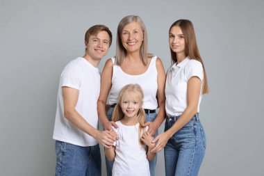 Açık gri arka planda oğlu ve ailesiyle birlikte son sınıf öğrencisi bir kadının portresi.