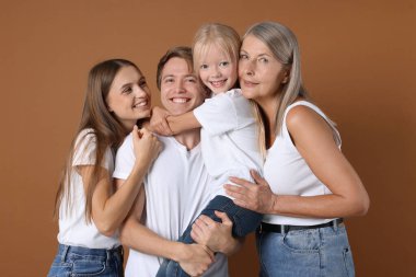 Kahverengi arka planda oğlu ve ailesi olan yaşlı bir kadının portresi.