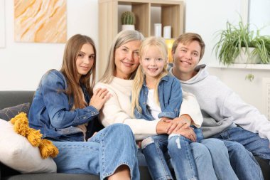 Oğlunun ailesiyle birlikte evdeki kanepede oturan yaşlı kadın.