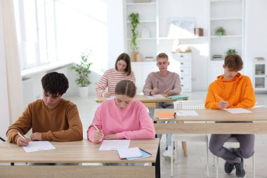 Ahşap masada sınava giren öğrenciler