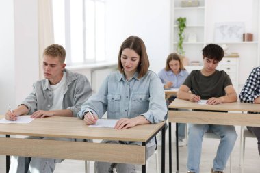 Ahşap masada sınava giren öğrenciler