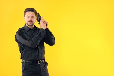 Sarı arka planda silahı olan üniformalı bir polis memuru, mesaj için yer var.