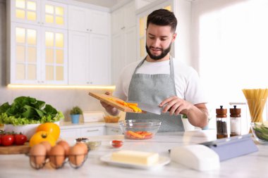 Mutfaktaki masada yemek pişiren gülümseyen adam.