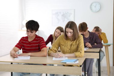 Ahşap masada sınava giren öğrenciler