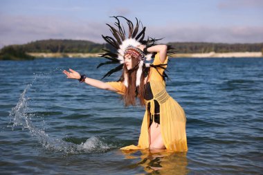 Kızılderili başlıklı güzel bir şaman kadın. Yüzü nehirde akan suyla boyanmış.