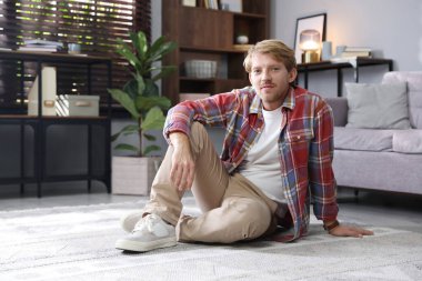 Adam evde yerde oturuyor, mesaj için yer var.