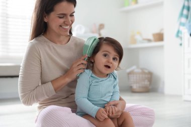 Anne banyoda bebeğinin saçını tarıyor.