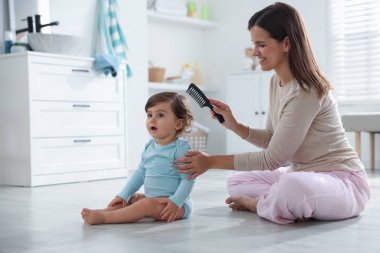 Anne banyoda bebeğinin saçını tarıyor.