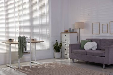 Yumuşak kanepe, masa, şifonyer ve ev bitkisi oturma odasında. İç tasarım