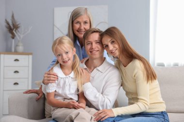 Oğlunun ailesiyle birlikte evdeki kanepede oturan yaşlı kadın.