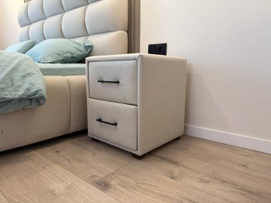 Yatak odasında lüks yatak ve şık komodiniyle rahat bir yatak.