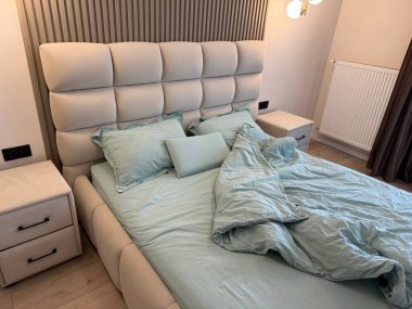 Yatak odasında yastıkları ve yorganı olan rahat büyük bir yatak.