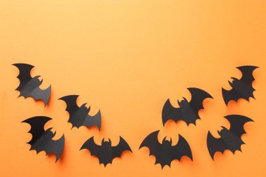 Cadılar Bayramı dekoru. Siyah kağıt yarasalar turuncu arka planda, düz yerde. Metin için boşluk