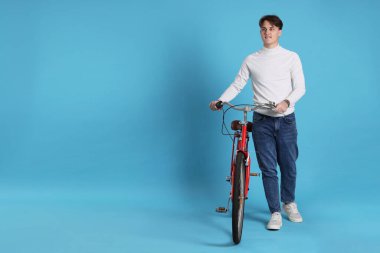 Açık mavi arka planda kırmızı bisikletli yakışıklı adam, metin için boşluk