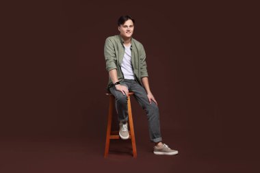 Kahverengi arka planda, kotlu şık bir adam.