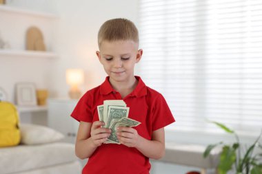 Evde cep harçlığı tutan küçük çocuk.