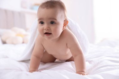 Evde banyo yaptıktan sonra beyaz havluyla tatlı bir bebek.