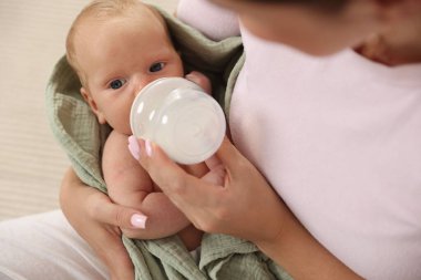 Anne yeni doğmuş bebeğini biberonla besliyor.