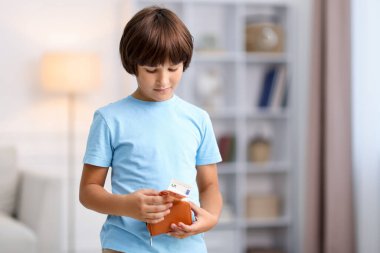 Çocuk cep harçlığını evdeki cüzdanına koyuyor.