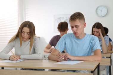 Ahşap masada sınava giren öğrenciler