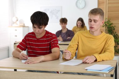 Ahşap masada sınava giren öğrenciler