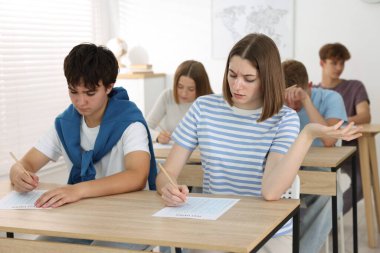 Ahşap masada sınava giren öğrenciler