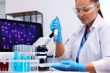 Genetik araştırması. Bilim adamı laboratuardaki masada mikro pipetle örnek alıyor.