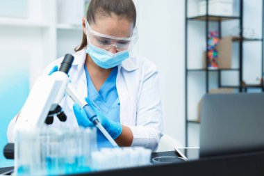 Genetik araştırması. Bilim adamı laboratuardaki masada mikro pipetle örnek alıyor.