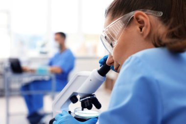 Genetik araştırması. Laboratuvarda mikroskopla çalışan bilim adamı, seçici odaklanma